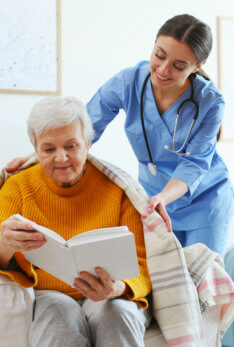 caregiver wrapping senior woman in blanket