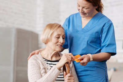 caregiver giving medicine to senior woman